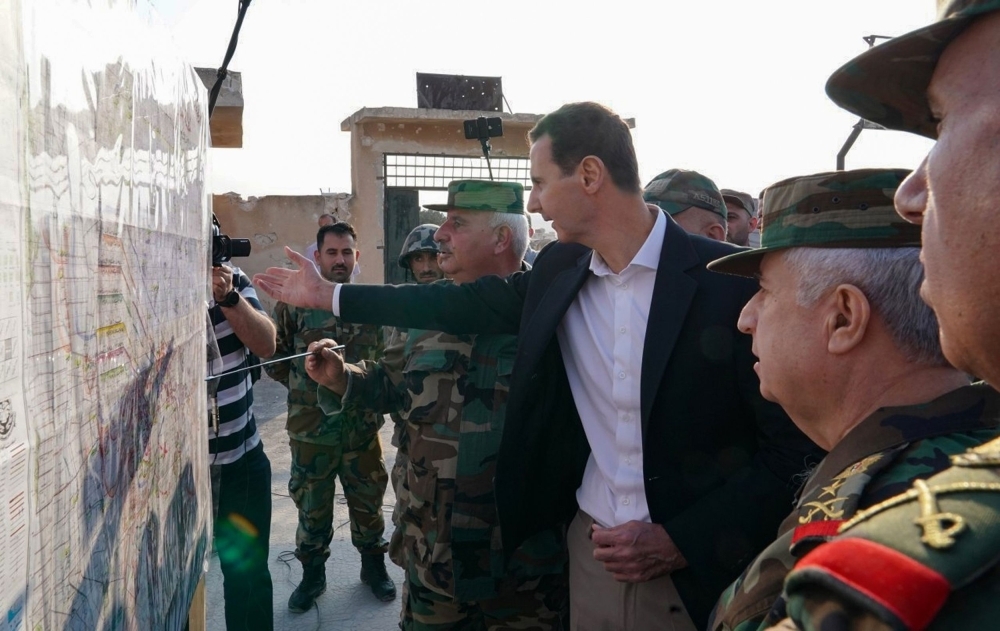 A handout picture released by the official Facebook page for the Syrian Presidency on Monday shows Syrian President Bashar Assad discussing a military map with  army officers in Aal-Habit on the southern edges of the Idlib province. — AFP