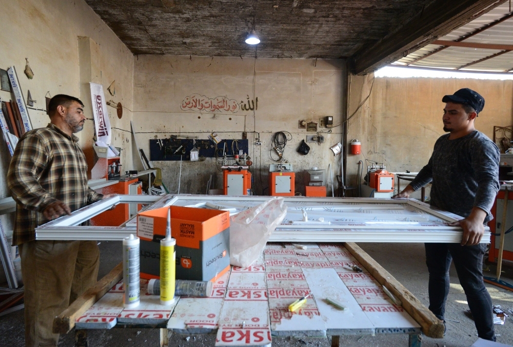 Iraqi men work at at a factory that makes windows and doors from aluminum and plastic in an industrial area east of the northern city of Mosul in this Sept. 30, 2019 file photo. — AFP