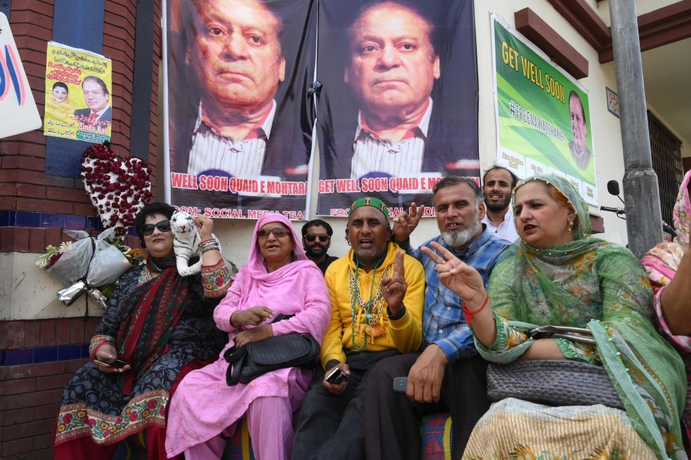 Supporters of Pakistani former Prime Minister Nawaz Sharif sit next to his pictures outside a hospital as he was admitted after his condition deteriorated, in Lahore, Pakistan, on Wednesday. — AFP