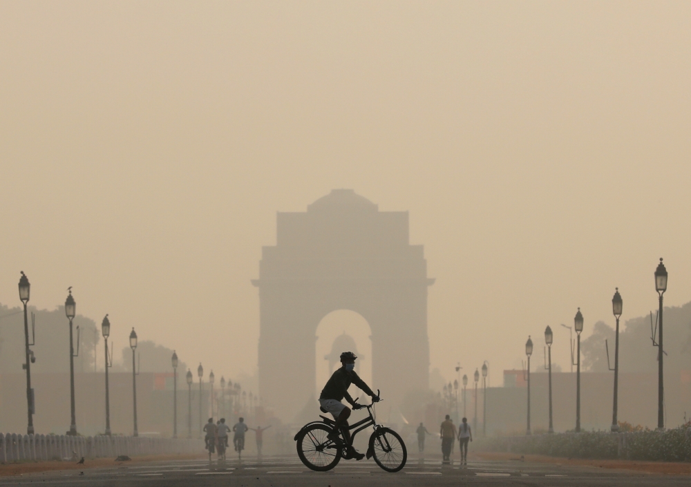 A man rides a bicycle on a smoggy morning near India Gate in New Delhi, India, Oct. 17, 2019. — Reuters