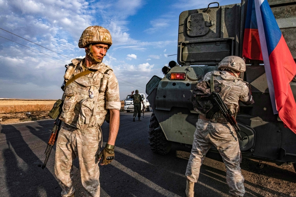 Russian military police members stand outside an armored vehicle along a road in the countryside near the northeastern Syrian town of Amuda in Hasakeh province on Thursday, as part of a joint patrol between Russian forces and Syrian Kurdish Asayish internal security forces near the border with Turkey. Russian forces have started patrols along the flashpoint frontier, filling the vacuum left by a US troop withdrawal that effectively returned a third of the country to the Moscow-backed regime of President Bashar Al-Assad. — AFP