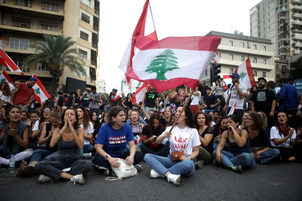 Lebanese protesters sit on the ground to block a major bridge in the center of the capital Beirut during an anti-government demonstration on Saturday. Demonstrators across Lebanon blocked roads and took to the streets today for a 10th consecutive day, defying what they said were attempts by Hezbollah to defuse their movement and despite tensions with the army. — AFP