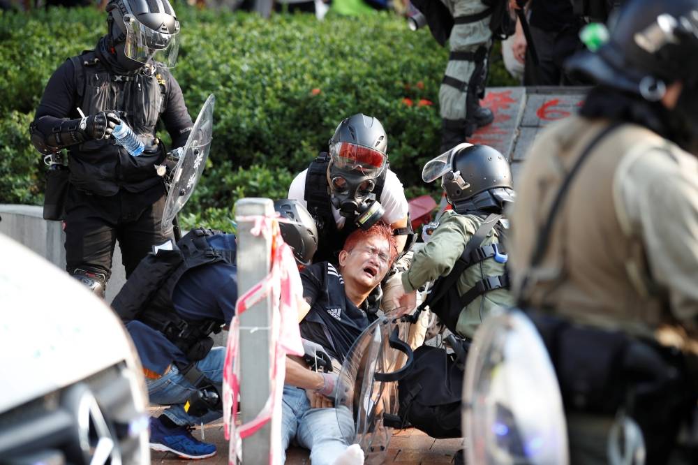 A man receives medical attention after being affected with a pepper spray as he is being detained during an anti-government protest in Hong Kong's tourism district of Tsim Sha Tsui, Sunday. — Reuters