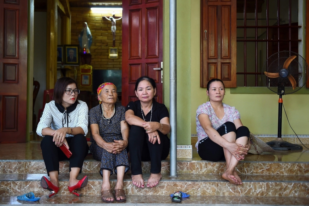 Relatives of 33-year old of Nguyen Van Hung who is feared to be among the 39 people found dead in a truck in Britain, sit outside a house house in Dien Chau district of Vietnam's Nghe An province on Monday. — AFP