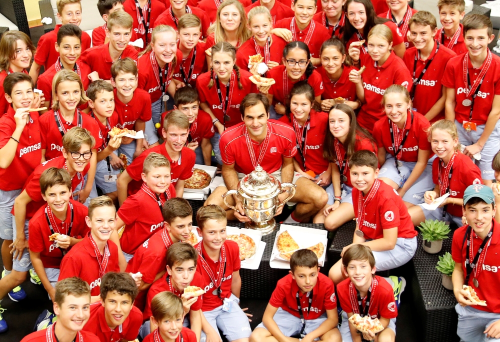 Switzerland's Roger Federer poses together with the Swiss Indoors tournament's ball boys and girls as they eat pizza after winning the final against Australia's Alex de Minaur at St. Jakobshalle, Basel, Switzerland, on Sunday. — Reuters