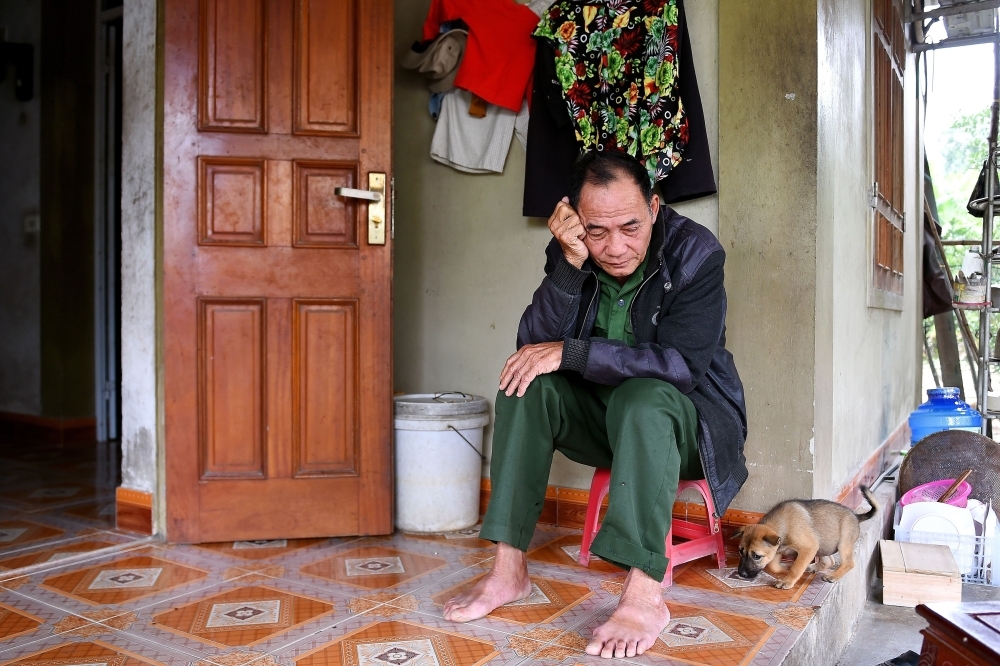 Bui Phan Chinh, father of 37-year-old of Bui Phan Thang who is feared to be among the 39 people found dead in a truck in Britain, sits outside his house in Hong Linh district of Vietnam's Ha Tinh province on Tuesday. — AFP