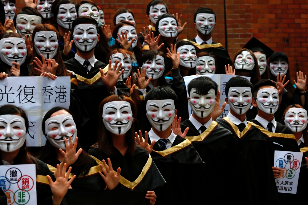 University students wearing Guy Fawkes masks pose for a photoshoot of a graduation ceremony to support anti-government protests at the Hong Kong Polytechnic University, in Hong Kong, on Wednesday. -Reuters