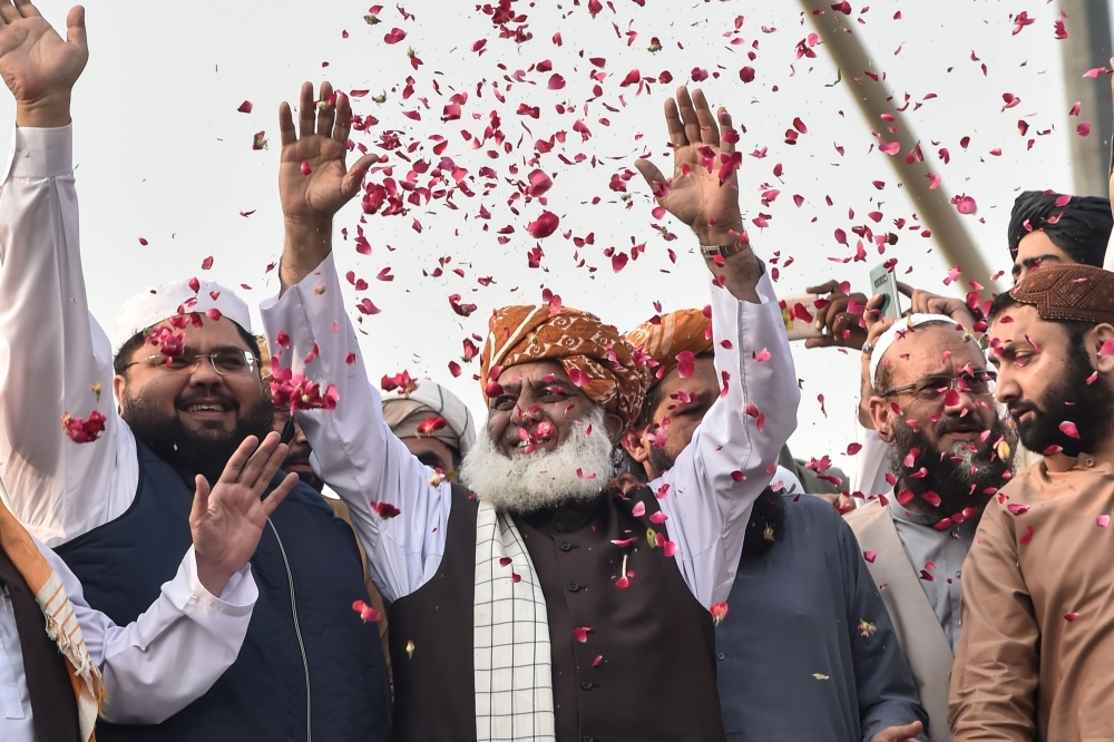 Chief of the Jamiat Ulema-e-Islam party Maulana Fazlur Rehman, center, gestures to supporters on his arrival during an anti-government 