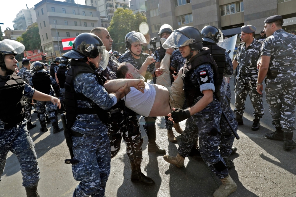 Lebanese riot police officers remove anti-government protesters as they dismantle a roadblock in the ring-bridge in the Lebanese capital Beirut on Thursday. — AFP