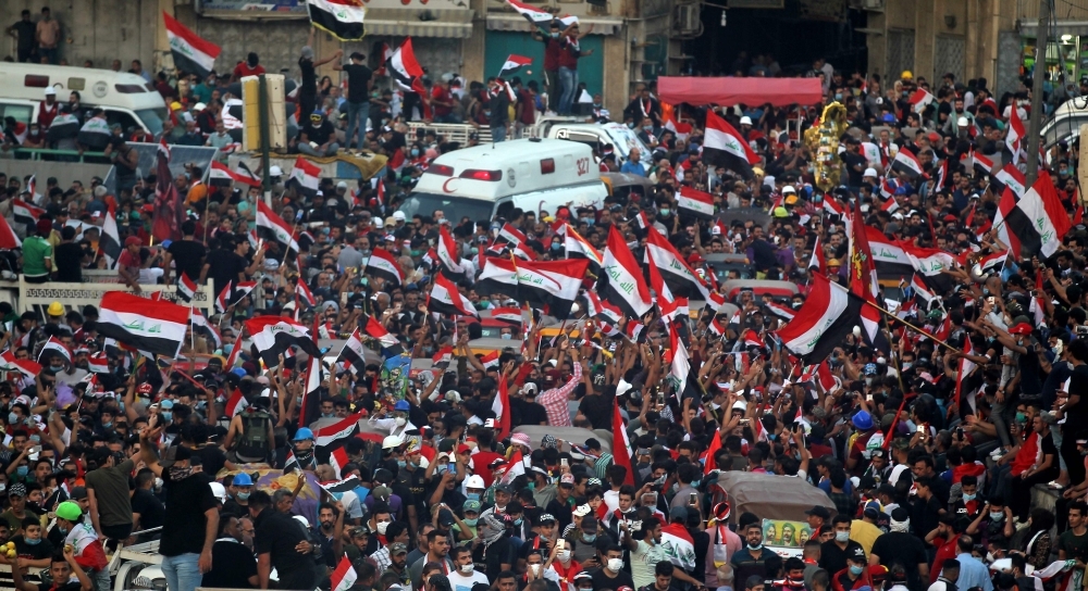 Iraqi demonstrators chant slogans and wave their country's national flags during ongoing anti-government demonstrations at Tahrir Square in the capital Baghdad on Wednesday. — AFP