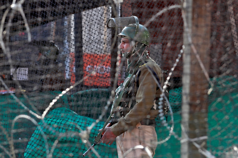 An Indian policeman stands guard outside a bunker alongside a road in Srinagar on Thursday. — Reuters