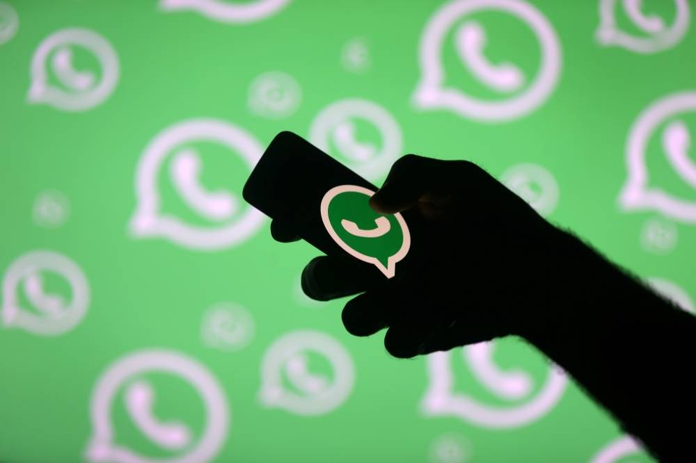 A man poses with a smartphone in front of displayed Whatsapp logo in this illustration on Sept. 14, 2017 file photo. — Reuters