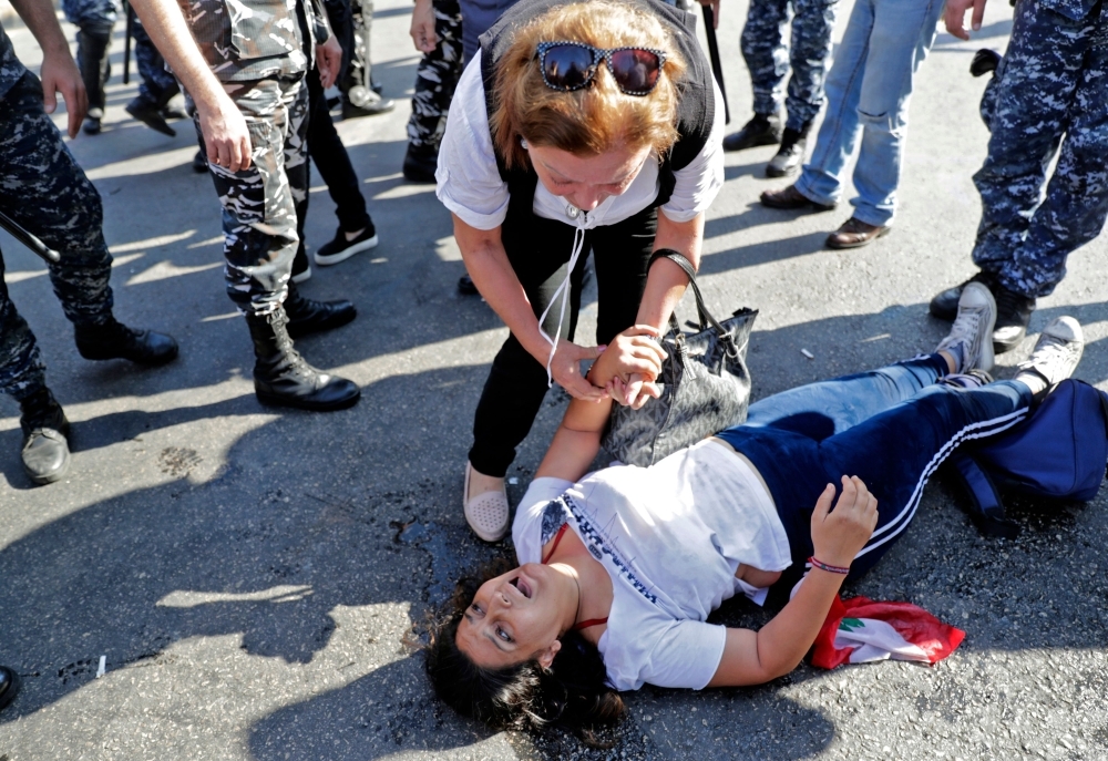 TOPSHOT - A Lebanese protester looses consciousness as riot police officers remove anti-government protesters blocking the road at the ring-bridge in the Lebanese capital Beirut on October 31, 2019. Demonstrators kept up their roadblocks across Lebanon today, as their unprecedented protest movement demanding systemic political change entered its third week. Traffic came to a standstill on major highways, as protesters erected metal barricades.
 / AFP / ANWAR AMRO
