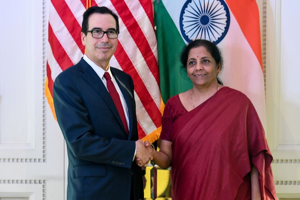India's Finance Minister Nirmala Sitharaman, right, and US Secretary of the Treasury Steven Mnuchin pose for photographs as they shake hands during a meeting in New Delhi on Friday. — AFP