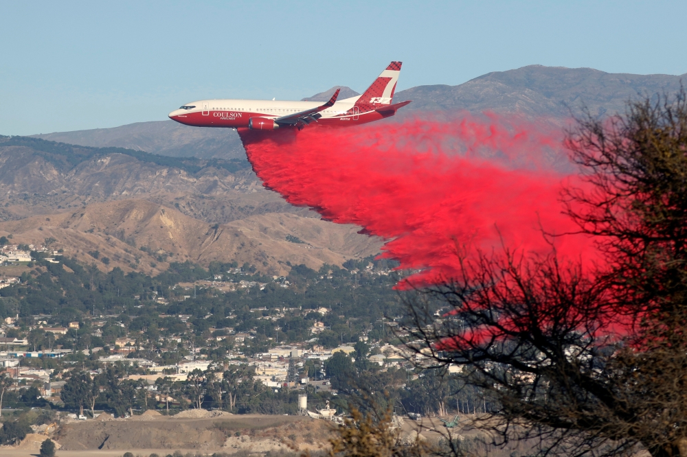 A plane drops fire retardant on the Maria Fire in the early morning in Santa Paula, California, on Friday. -AFP