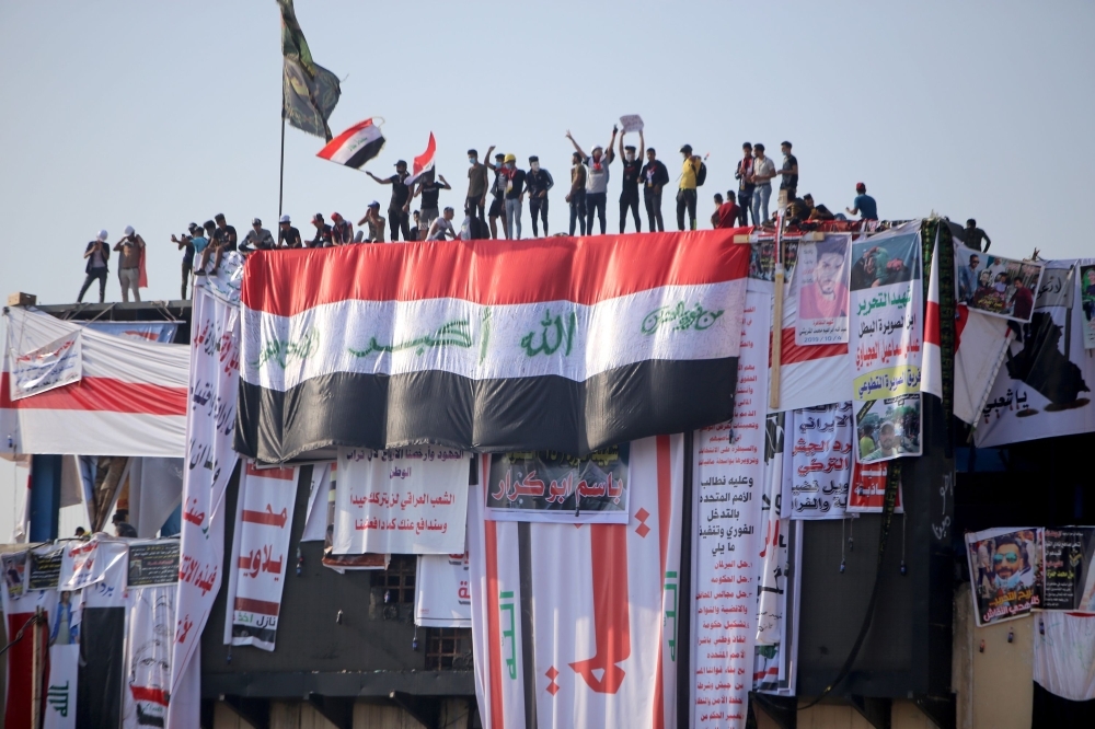 Iraqi demonstrators gather at an abandoned building in the capital Baghdad, overlooking the Tahrir square and the Al-Jumhuriya bridge that leads to the high-security Green Zone, which hosts government offices and foreign embassies, during the ongoing anti-government protests on Saturday. -AFP