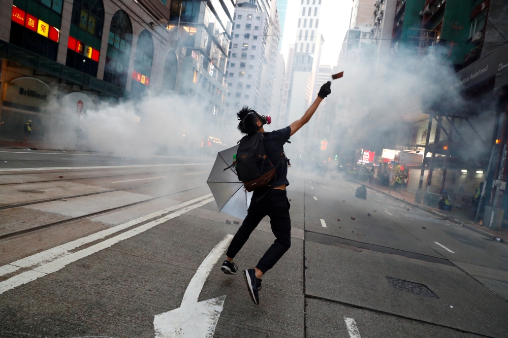 An anti-government protester reacts as police fire tear gas during a march billed as a global 