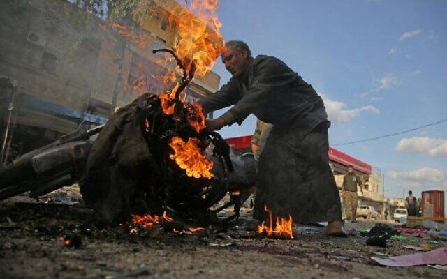 A Syrian man stands next to a burning motorcycle at the site of a car bomb explosion in the northern Syrian Kurdish town of Tal Abyad, on the border with Turkey, on Saturday. -AFP