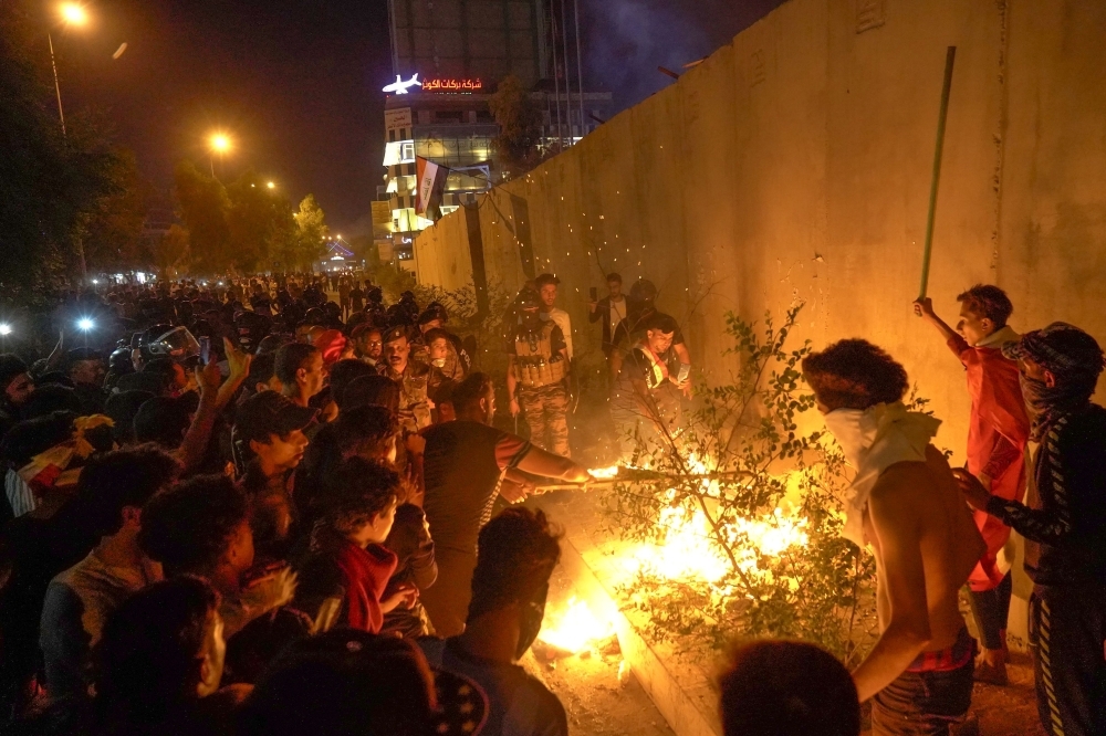 Iraqi demonstrators set tires ablaze behind the walls protecting the Iranian consulate in the Shiite Muslim shrine city of Karbala, south of Iraq's capital Baghdad, during Sunday night. — AFP