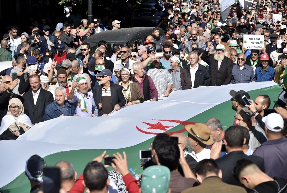 Algerian protesters march with a giant national flag in the centre of the capital Algiers as anti-government demonstrations continue on November 5, 2019.    Despite fierce opposition from the streets, Algerian authorities have been pushing forward with presidential elections set for December 12. / AFP / RYAD KRAMDI                         
