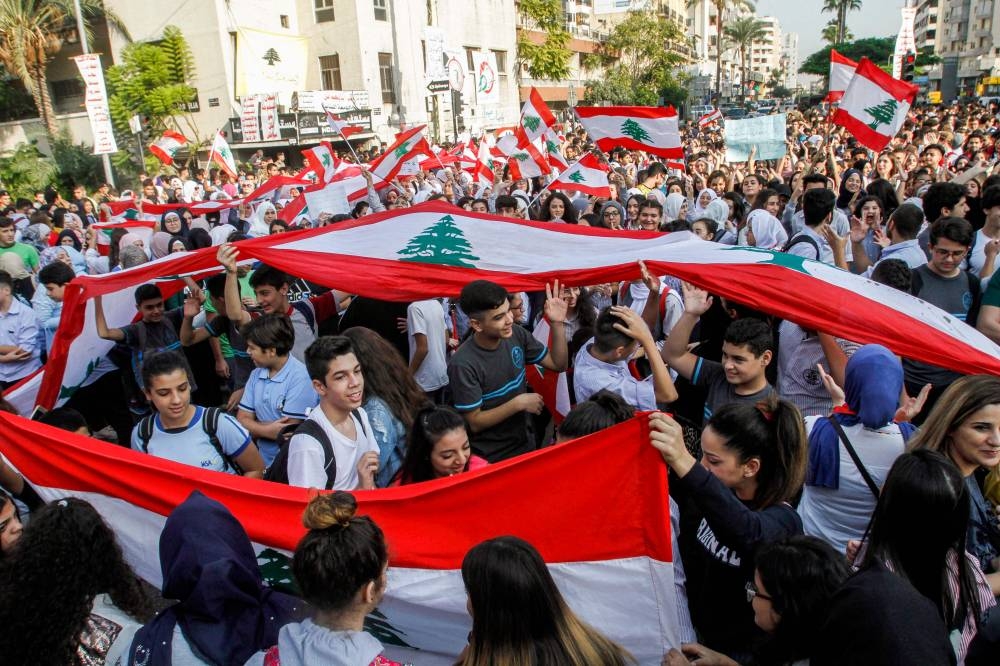 Lebanese students wave national flags and chant slogans as they gather in an anti-government demonstration in the southern city of Sidon on Wednesday. — AFP
