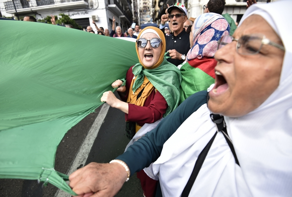 Algerian protesters hold a giant national flag in the center of the capital Algiers as anti-government demonstrations continue on Tuesday. — AFP