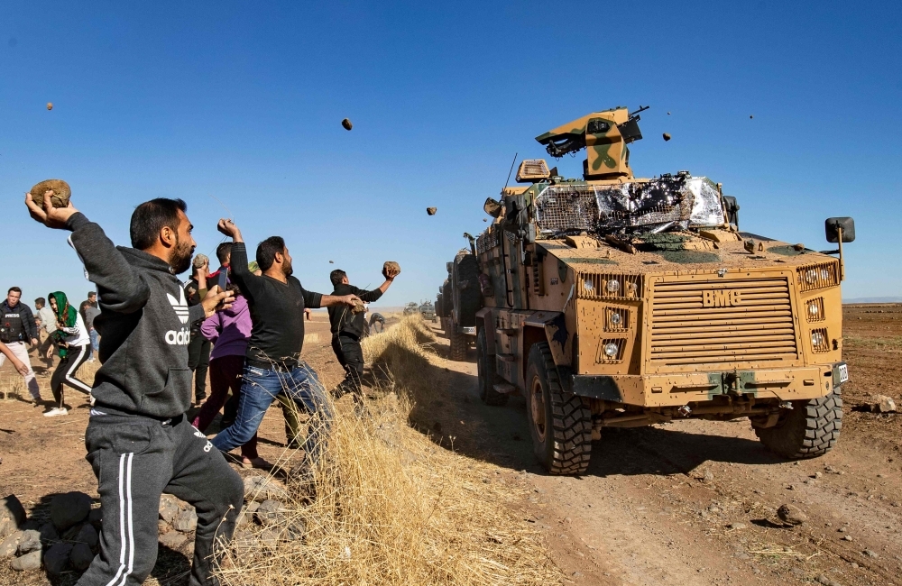  Kurdish demonstrators hurl rocks at a Turkish military vehicle on Friday, during a joint Turkish-Russian patrol near the town of Al-Muabbadah in the northeastern part of Hassakah on the Syrian border with Turkey. -AFP