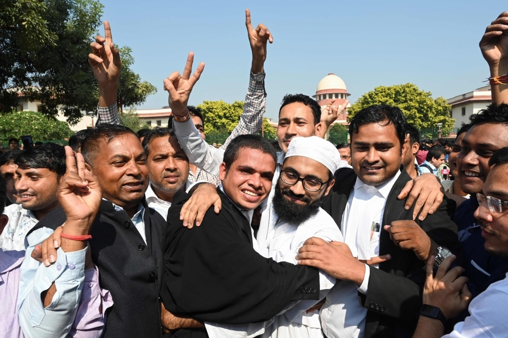 Lawyers and supporters hug a Muslim man at the Supreme Court in New Delhi on Saturday, after a ruling over a holy site contested for centuries by Hindus and Muslims. -AFP