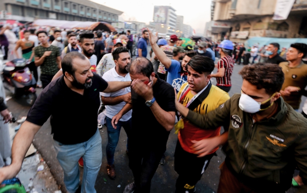 A wounded Iraqi demonstrator rushes towards an ambulance during clashes with Iraqi forces in Al-Khalani square in central Baghdad on Saturday. Iraqi forces unleashed live ammunition as they pushed towards the capital's main anti-government protest camp, after political leaders agreed to stand up the government by any means — including force. — AFP