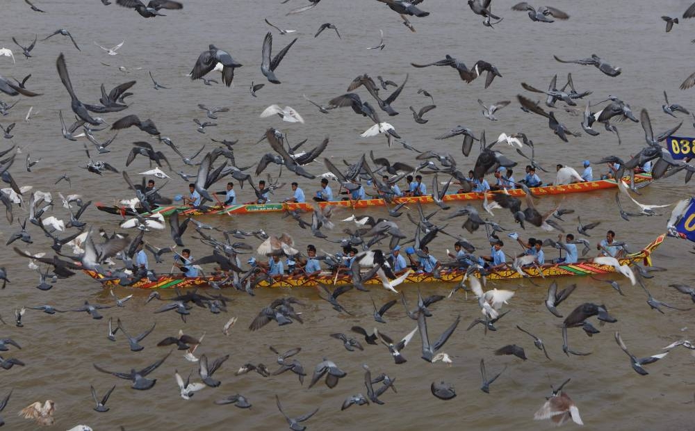 Cambodian participants row their dragon boats as pigeons fly past during the Water Festival on the Tonle Sap river in Phnom Penh. — AFP