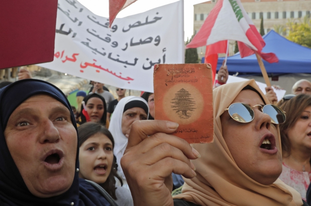 A Lebanese demonstrator raises an old identity card during a march entitled 