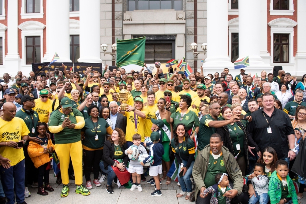 South African Rugby scrumhalf Faf de Klerk (C)  holds the Web Ellis Trophy, while the rest of the Springboks team stands beside him, during the South African Rugby World Cup winner team's last stop to parade the Web Ellis Trophy at the South African Parliment  in Cape Town on Monday. — AFP