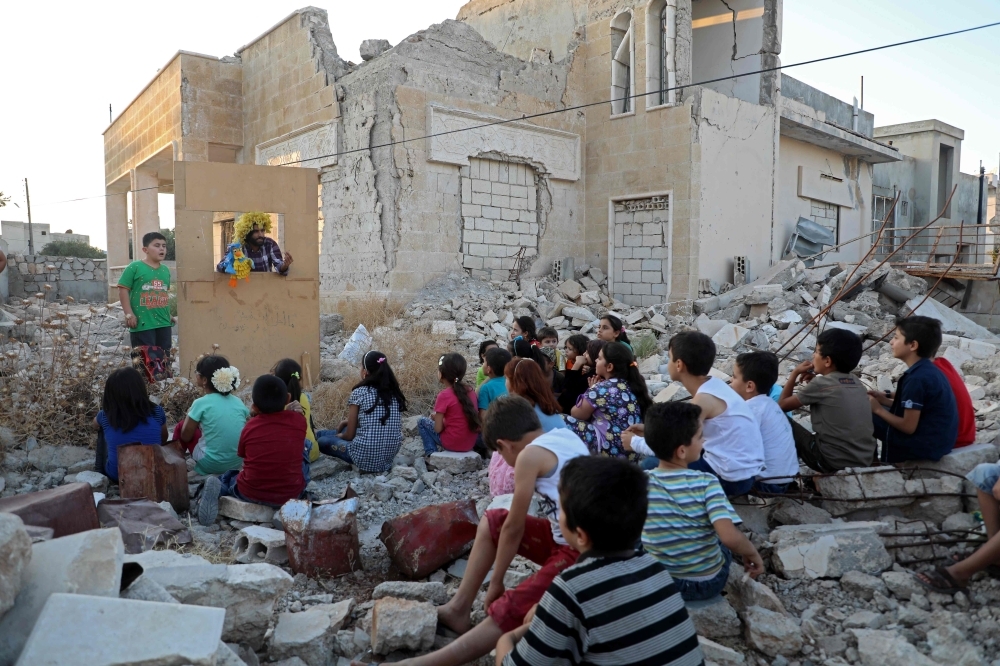 Syrian puppeteer Walid Abu Rashed performs a puppet act for children amid the rubble of damaged buildings in Syria's northwestern city of Saraqib in the Idlib province in this Sept. 29, 2019 file photo. — AFP