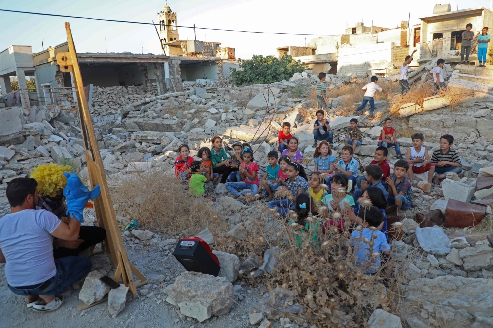 Syrian puppeteer Walid Abu Rashed performs a puppet act for children amid the rubble of damaged buildings in Syria's northwestern city of Saraqib in the Idlib province in this Sept. 29, 2019 file photo. — AFP