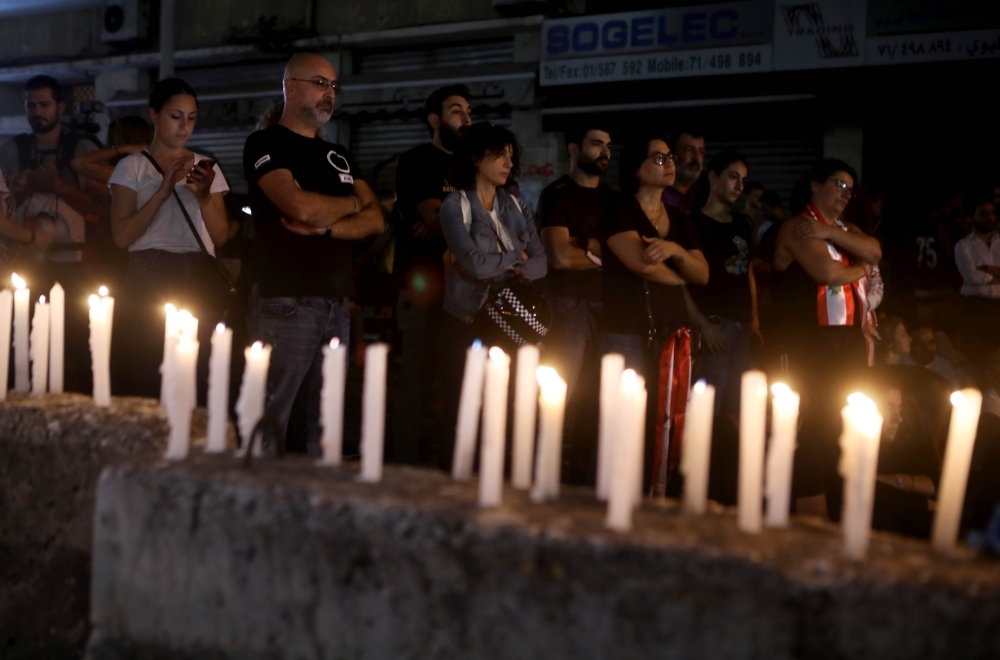 Lebanese anti-government protesters take part in a candle light vigil outside the headquarters of Lebanon Electricity company (EDL) in Beirut on Monday. — AFP