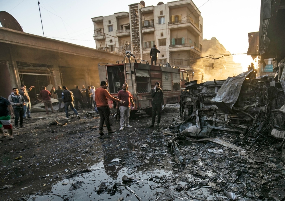 Security forces and civilians gather the site of bombings in the Syrian Kurdish-majority city of Qamishli in the northeastern Hasakah province, on Monday. — AFP