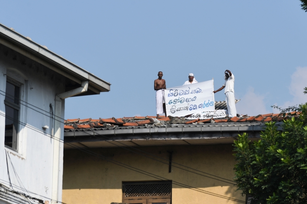 Special Task Force (STF) soldiers stand guard near the Welikada prison in Colombo on Tuesday, as inmates protest the pardon for a man who murdered a Swedish teenager in 2005. — AFP