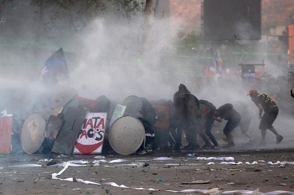 Demonstrators clash with security forces during a protest against the government of Sebastian Pinera in Santiago on Tuesday. -AFP  