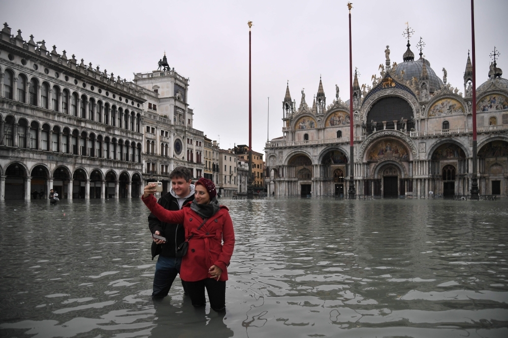 People take selfie photos at the flooded St. Mark's square by St. Mark's Basilica after an exceptional overnight 