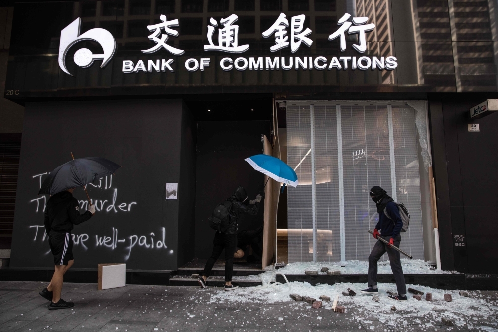 Protesters vandalize a branch of the Bank of Communications during a protest in the Central district in Hong Kong on Wednesday. -AFP 
