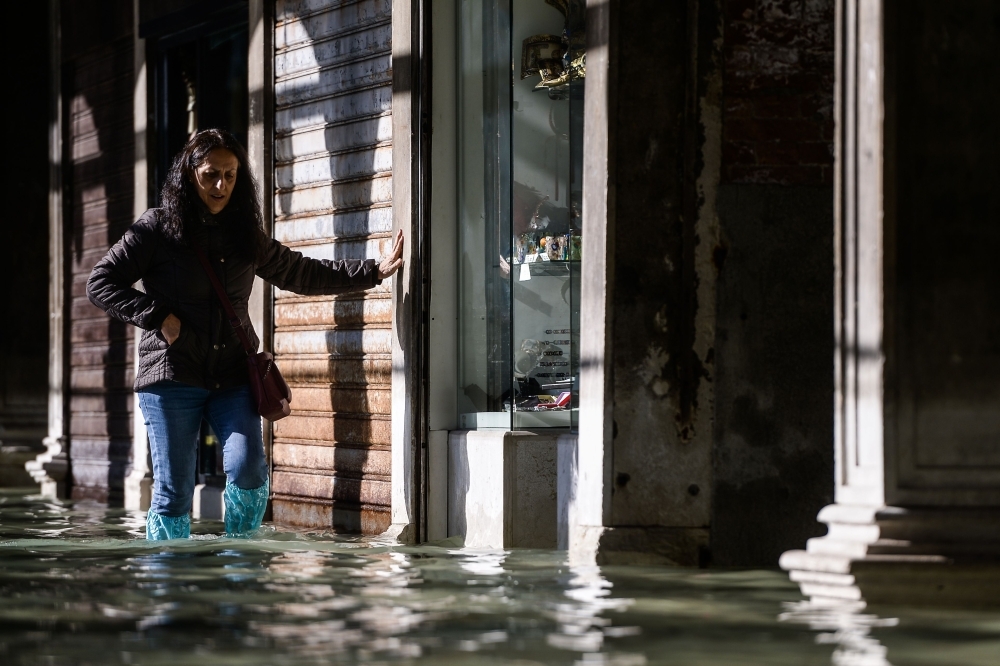 People walk on a footbridge across the flooded St. Mark's Square by St. Mark's Basilica, rear, and the Doge's palace, right, in Venice, Italy, on Thursday. — AFP