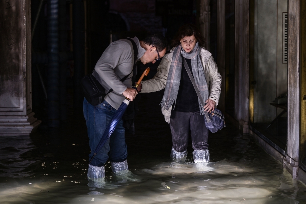 People walk on a footbridge across the flooded St. Mark's Square by St. Mark's Basilica, rear, and the Doge's palace, right, in Venice, Italy, on Thursday. — AFP