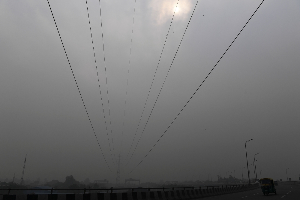 Commuters drive along a motorway under heavy smog conditions in New Delhi on Thursday. — AFP