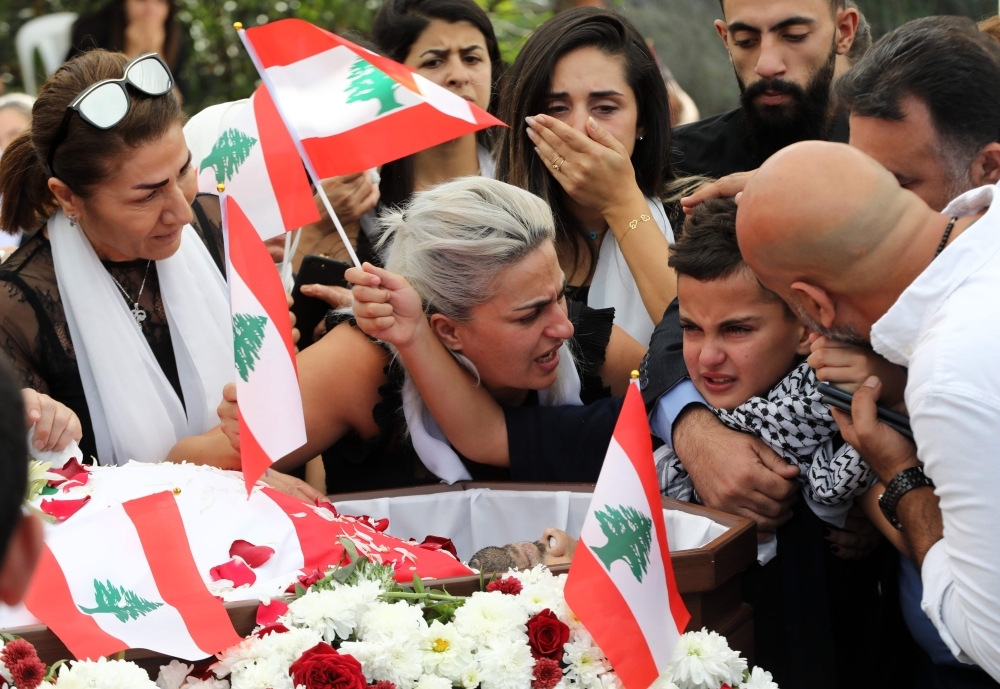 The coffin of slain Lebanese protester Alaa Abu Fakhr, draped in a national flag, is carried  by mourners through the streets of his hometown of Chouaifet, southeast of Beirut, during his funeral procession on Thursday. — AFP