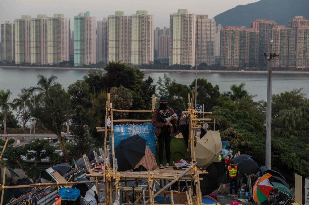 A protester, center, stands among bricks placed on a barricaded street outside The Hong Kong Polytechnic University in Hong Kong on Friday. — AFP