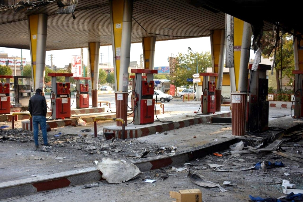 An Iranian man checks a scorched gas station that was set ablaze by protesters during a demonstration against a rise in gasoline prices in Eslamshahr, near the Iranian capital of Tehran, on Sunday. — AFP