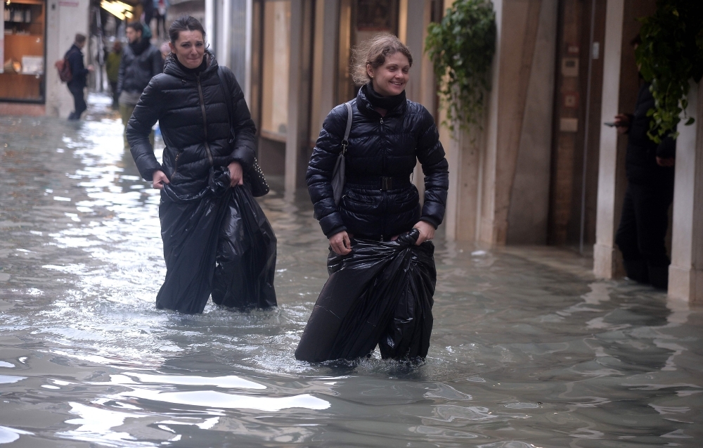 Visitors walk at the sunset in the flooded street in Venice, during 