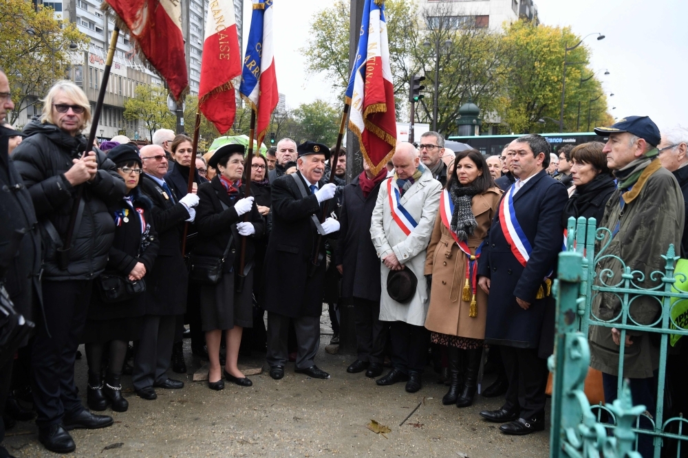 Paris' mayor Anne Hidalgo (first row, 4thR) and mayor of Paris' 13th district Jerome Coumet (first row, 3rdR) spend a moment in silence, on Monday at Place d'Italie in Paris in front of the  the damaged monument to World War II hero Marshal Alphonse Juin which was defaced by demonstrators dressed in black two day ago during the 