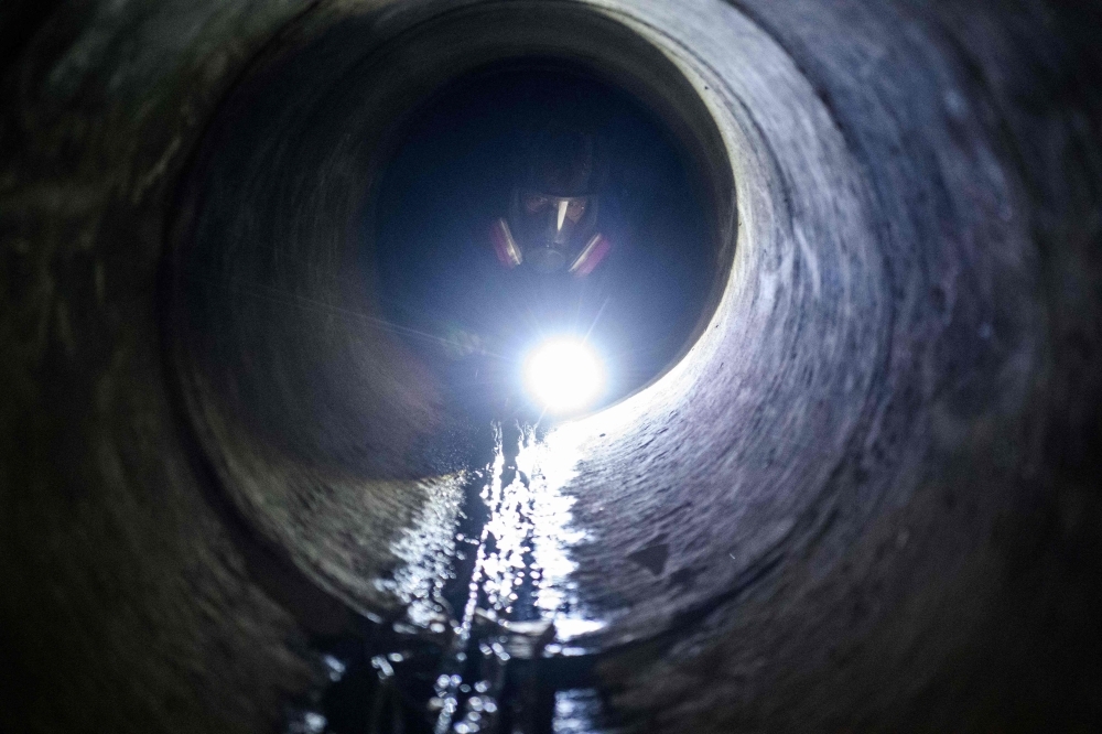 A protester crawls within a sewer tunnel to see how wide it is as he and others try to find an escape route from the Hong Kong Polytechnic University in the Hung Hom district of Hong Kong early morning on Tuesday. — AFP