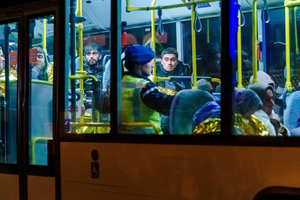 A bus with refugees drives away from the DFDS ferry, in the harbor of Vlaardingen, The Netherlands on Tuesday, after 25 stowaways were found onboard. -AFP